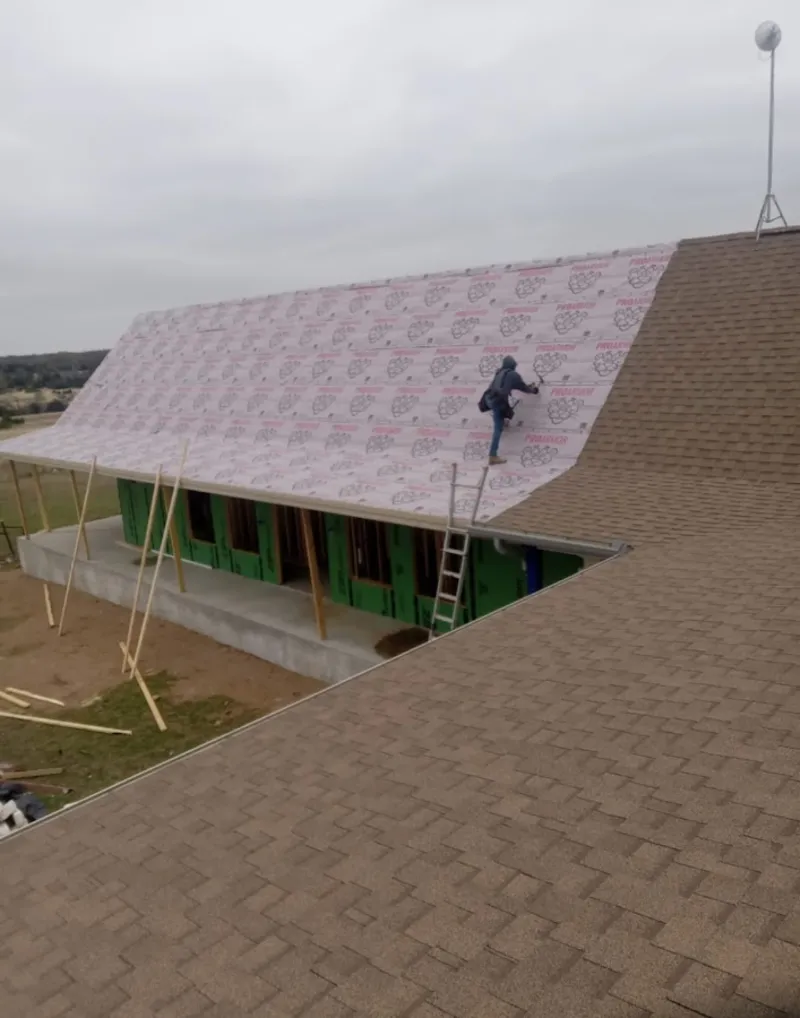 Worker preparing underlayment for a metal roof installation in Waseca